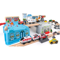 Hape -  Ensemble De Godets De Train Méga Métropole-Comprend 1 boîte avec 1 couvercle, 3 rails en plastique en S, 1 rail en Y, 4 rails courbes, 8 rails droits, 2 rails ascendants, 4 décorations en bois, 1 train de marchandises avec 2 wagons, 1 plateforme, 1 tour de guet, 1 avion, 1 feu tricolore, 1 camion de pompiers, 2 blocs incendie, 1 camion, 2 blocs cargo, 1 avion, 1 extrémité de piste, 1 taxi, 1 grue, 4 blocs d'arbres, 1 passage à niveau, 1 piste rocheuse, 1 montagne en plastique, 8 piliers, 1 moteur à 